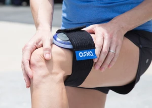 A person wearing an Oska Pulse device strapped around their knee